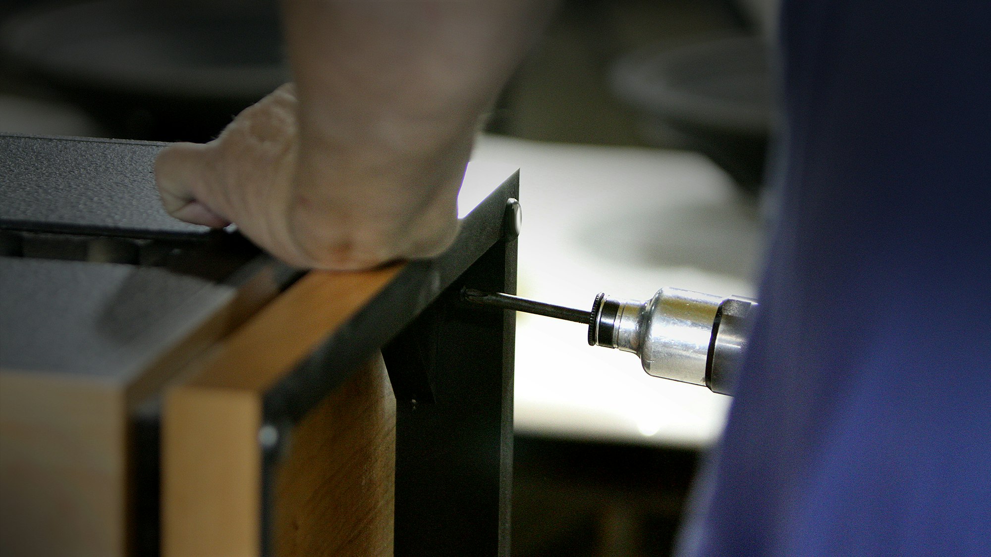 A close up view of a craftsman at the Hope Arkansas Klipsch Factory hand assembling a Heritage Speaker with a screwgun